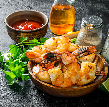 Ready shrimps on a plate with sauce, spices and herbs.